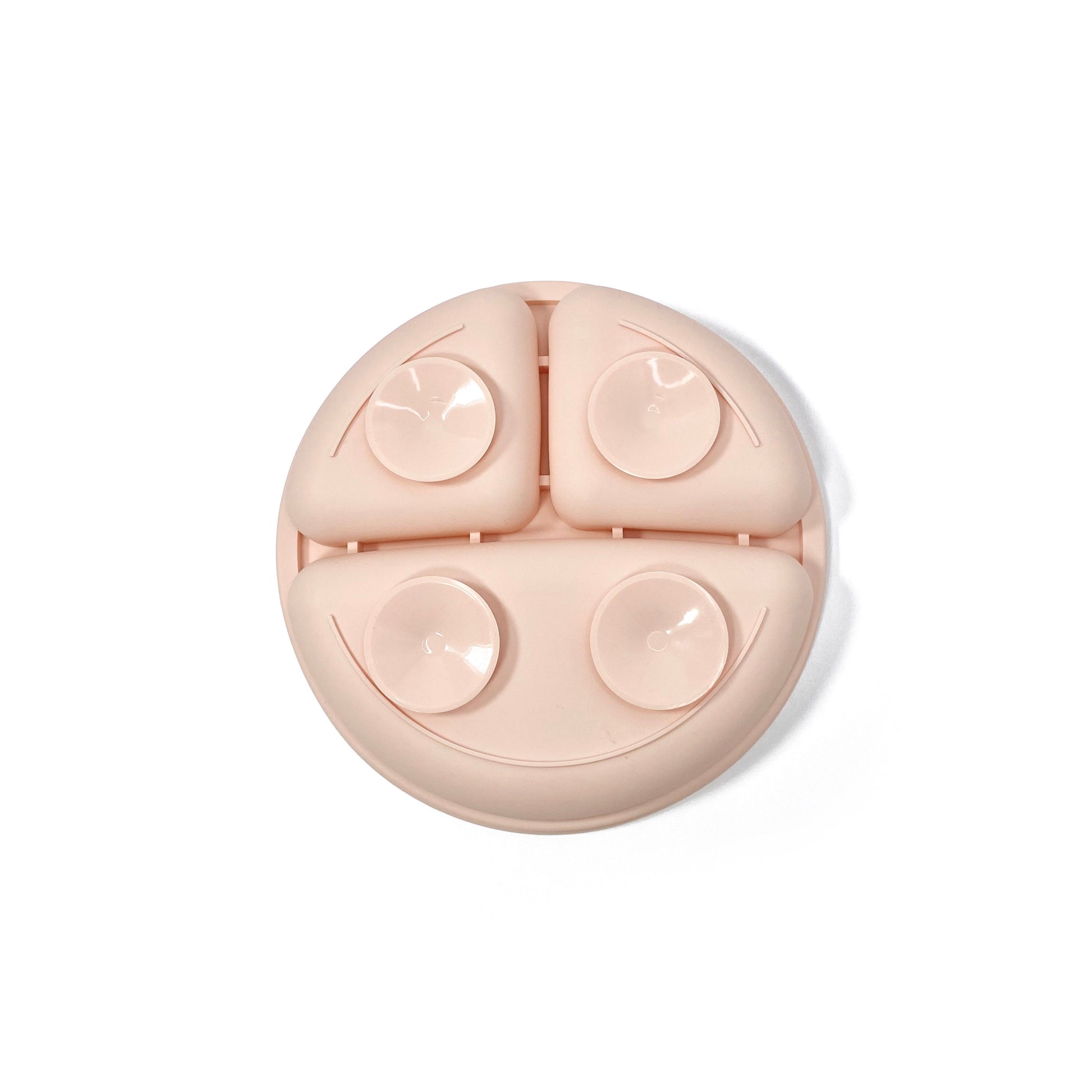 A peachy pink silicone children’s section plate with suction cups on the base. View shows the underside of the plate.