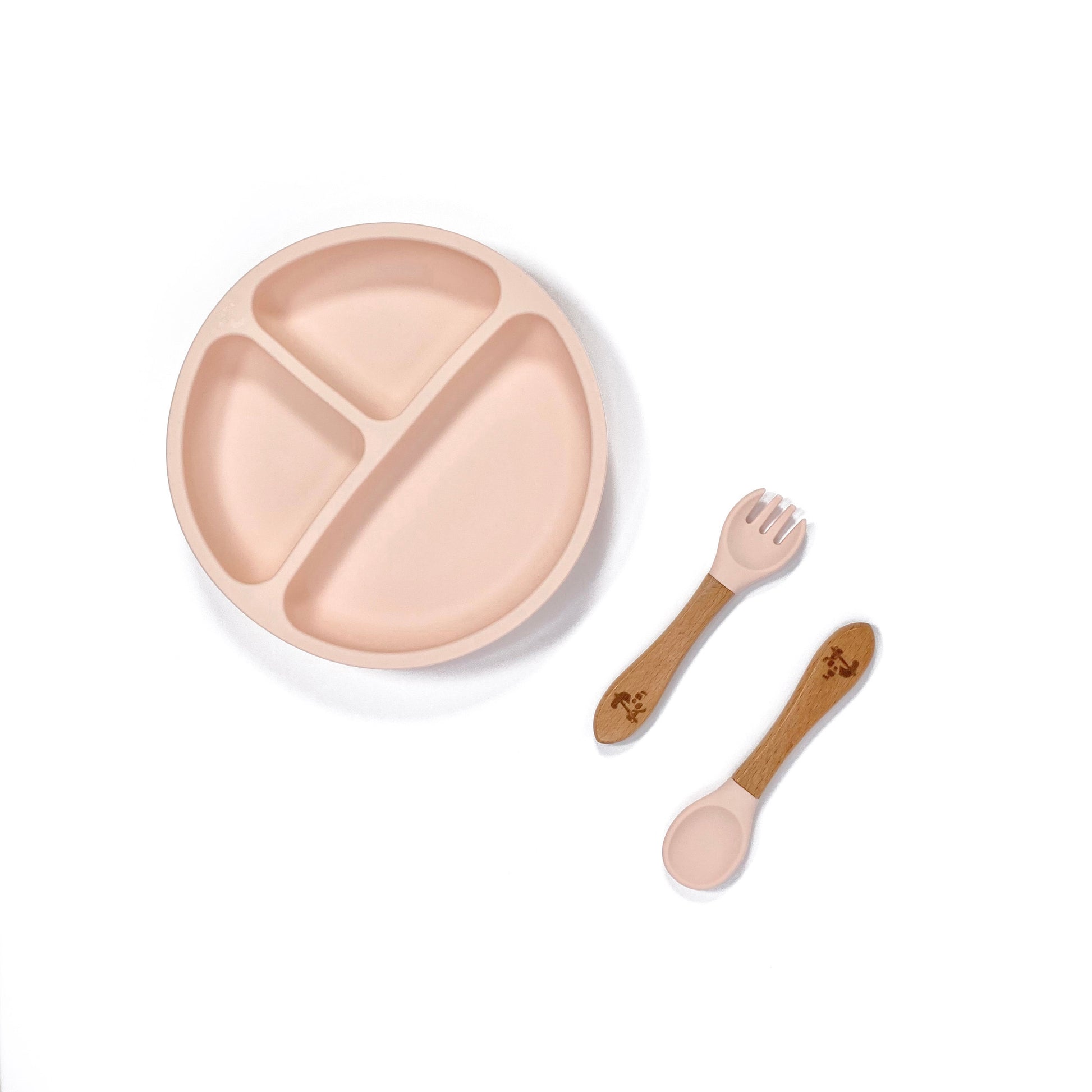 A peachy pink silicone children’s section plate with cups on the base, and matching bamboo and silicone cutlery.