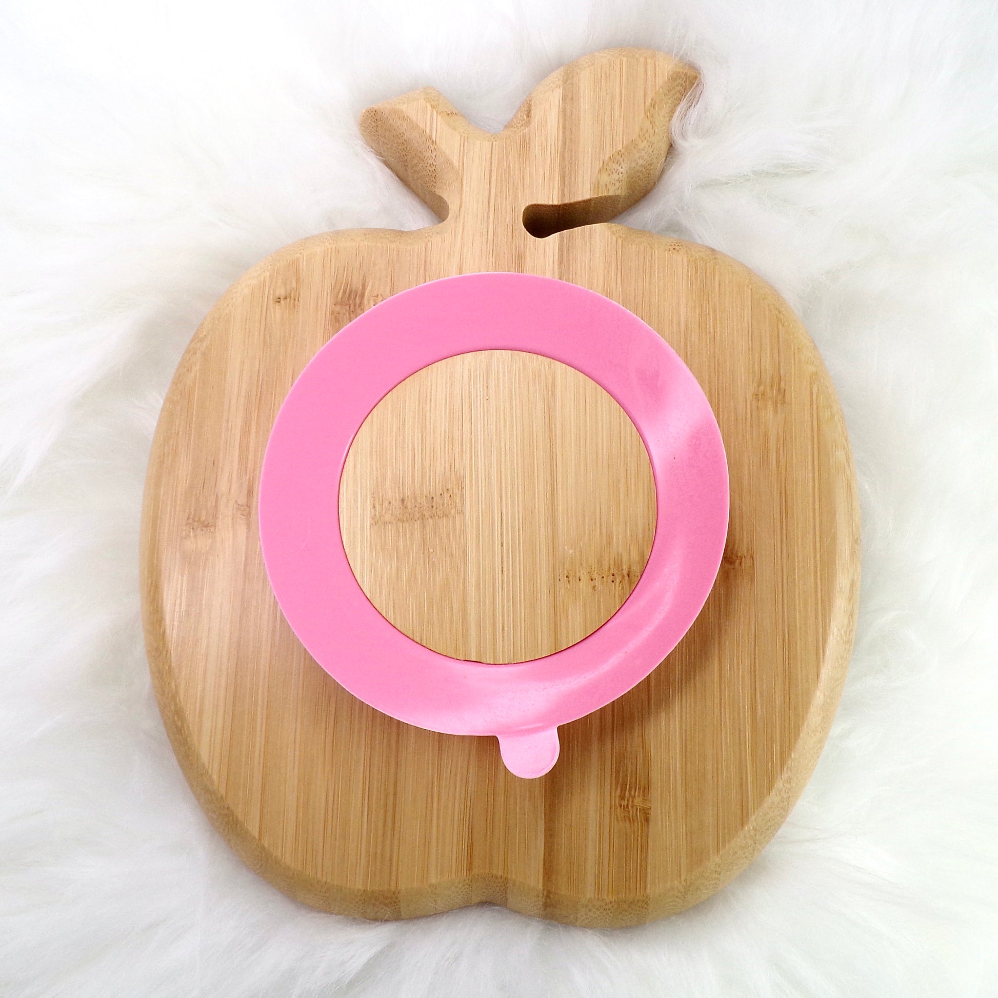 A bamboo children’s plate, with multiple food sections, in an apple design. The bamboo plate features a pink silicone suction ring at the back, and includes bamboo fork and spoon utensils in matching colours. Back view.