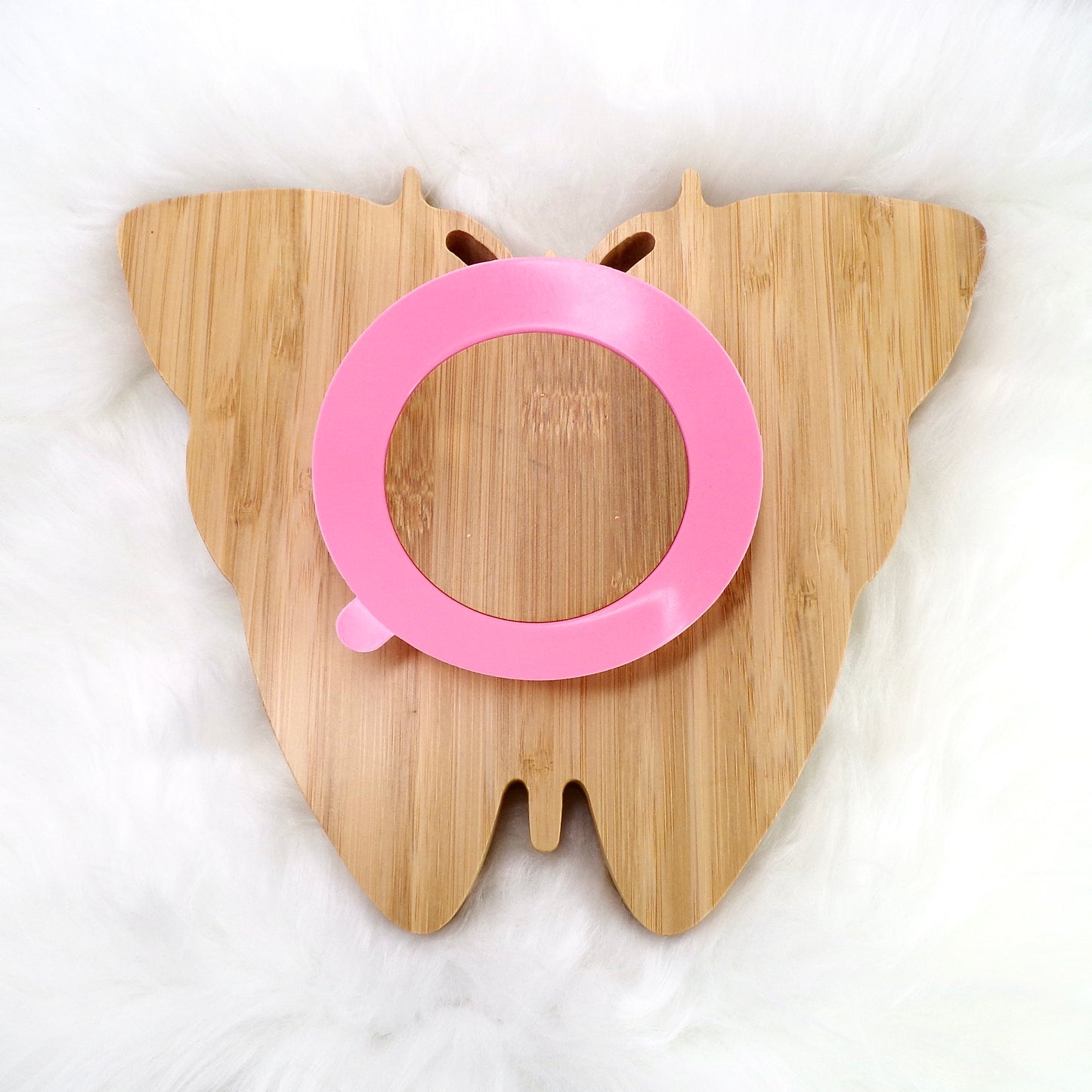 A children's bamboo section plate with a butterfly design, pink colour silicone suction ring and matching pink bamboo and silicone cutlery. Back view.