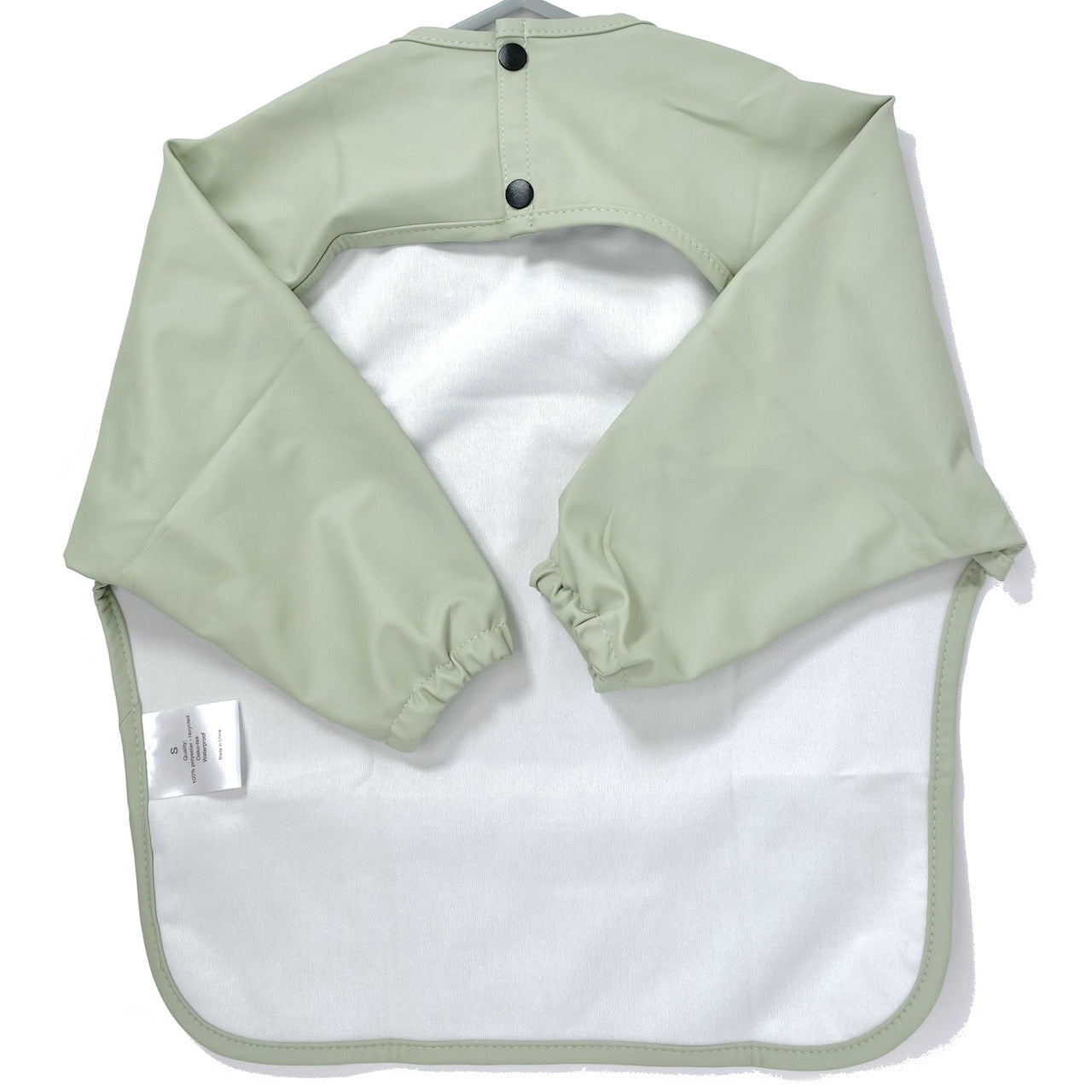 Long-sleeve kids apron in a pistachio green colour, showing front view.