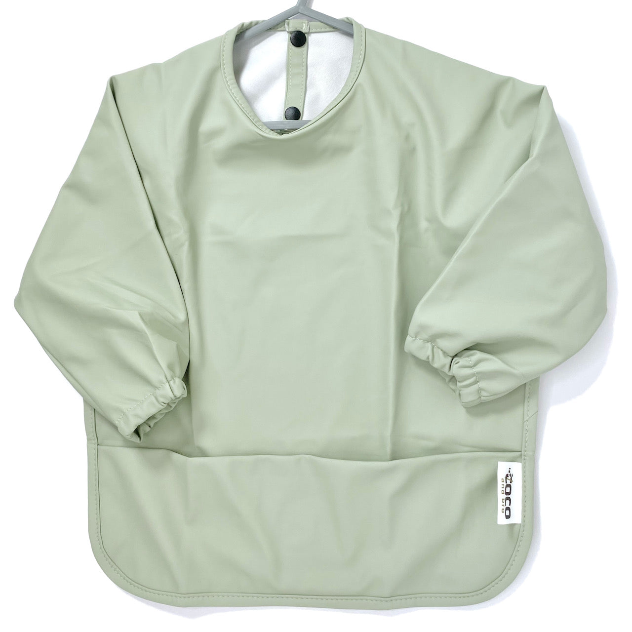 Long-sleeve kids apron in a pistachio green colour, showing front view.