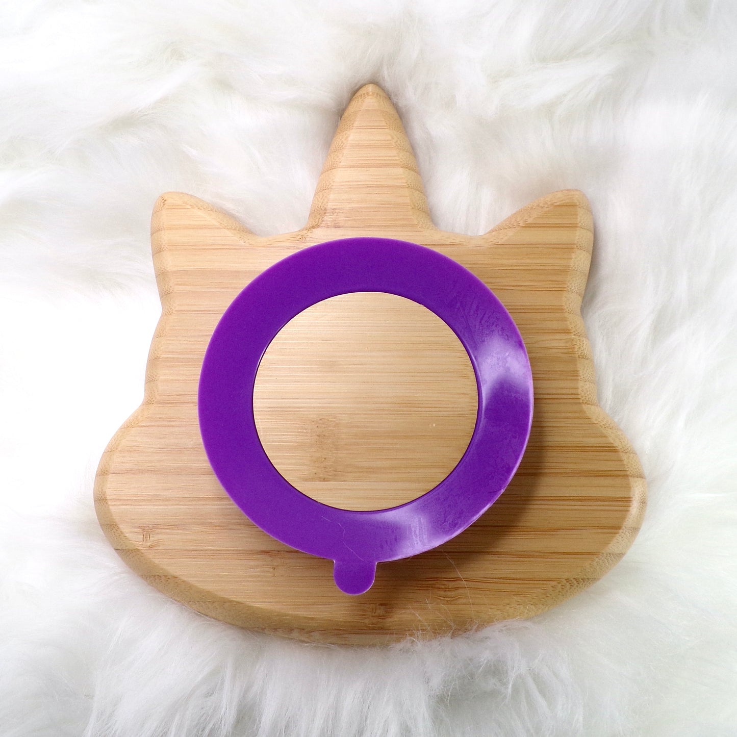 A bamboo children’s plate, with multiple food sections, in a unicorn design. The bamboo plate features a purple silicone suction ring at the back, and includes bamboo fork and spoon utensils in matching colours. Back view.