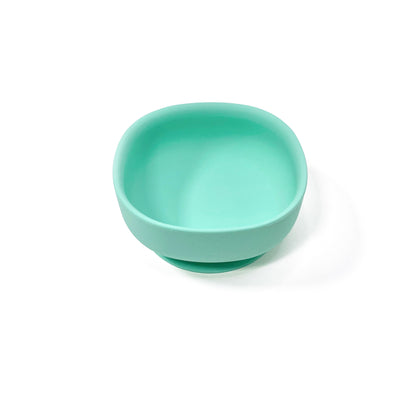 A seafoam green silicone children’s feeding bowl with suction cup on the base. Side view.