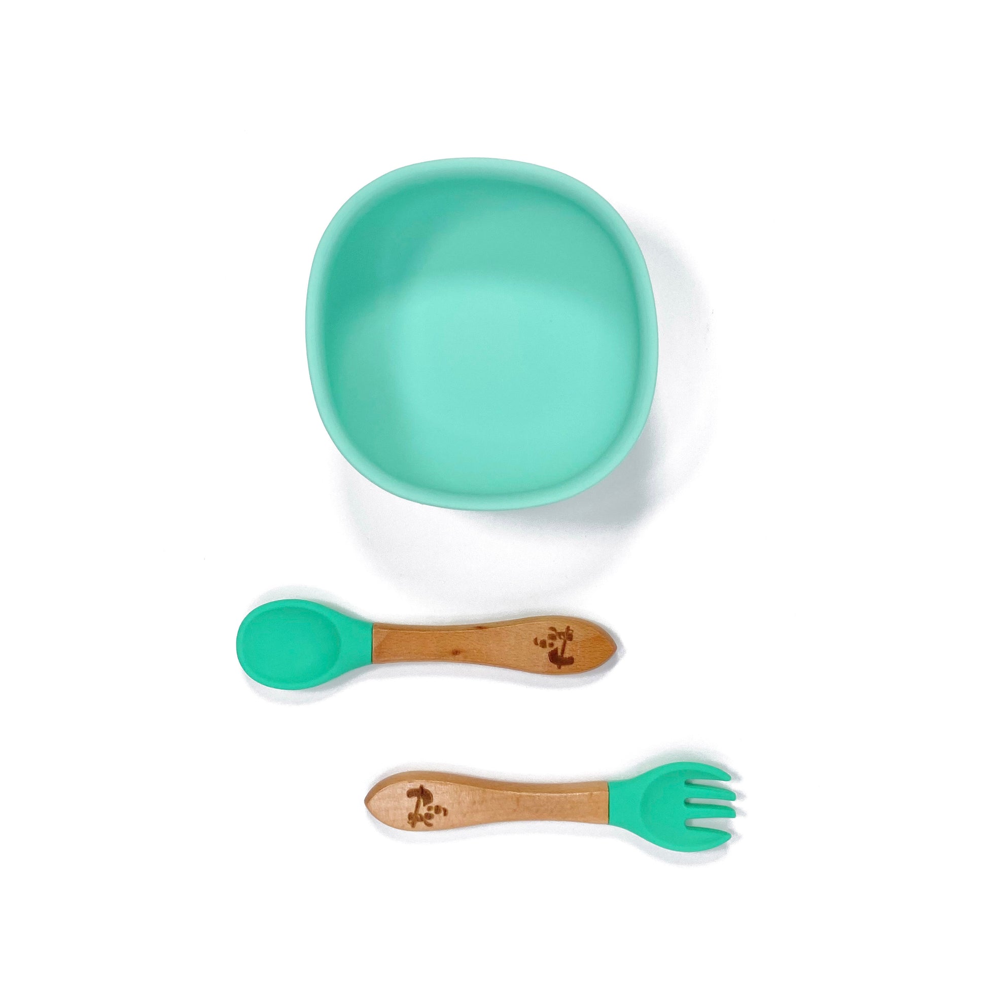 A seafoam green silicone children’s feeding bowl, with matching bamboo and silicone cutlery.