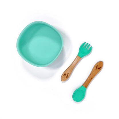 A seafoam green silicone children’s feeding bowl, with matching bamboo and silicone cutlery.