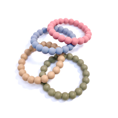 A range of beaded silicone teething rings, in green, beige, blue and pink.