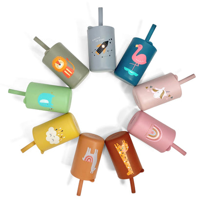 A collection of children’s silicone drinking cups with matching lids and straws, in various colours and designs, laid out in a circular pattern.