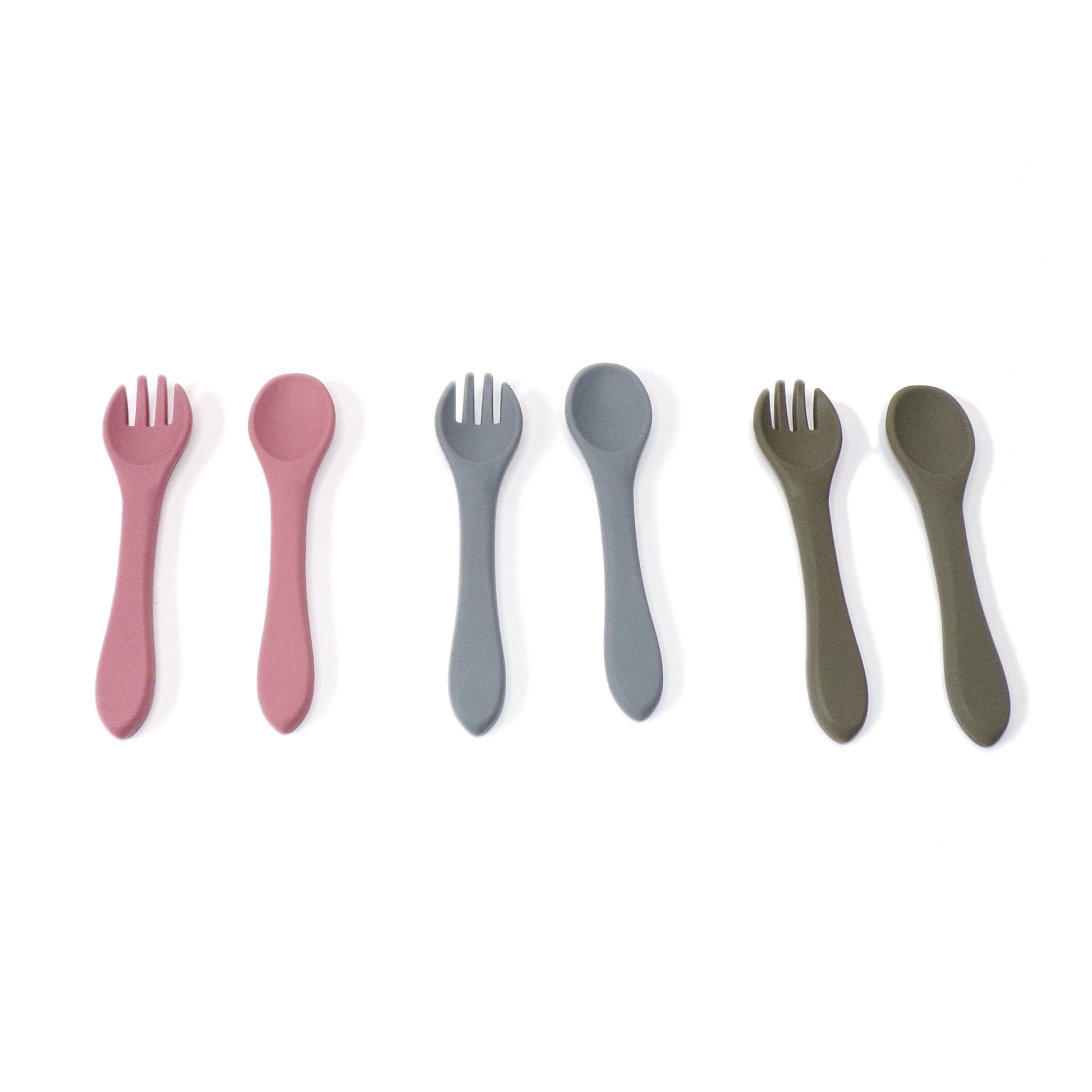 Three sets of silicone cutlery, a fork and spoon, in colours pink, blue and green. The utensils are designed for young children.