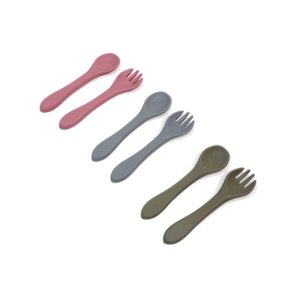 Three sets of silicone cutlery, a fork and spoon, in colours pink, blue and green. The utensils are designed for young children.