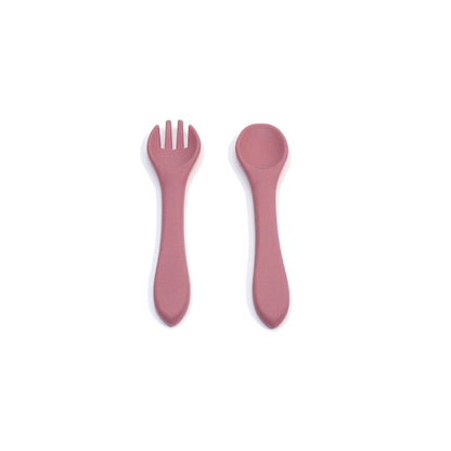 A set of pink silicone cutlery, a fork and spoon. The utensils are designed for young children.