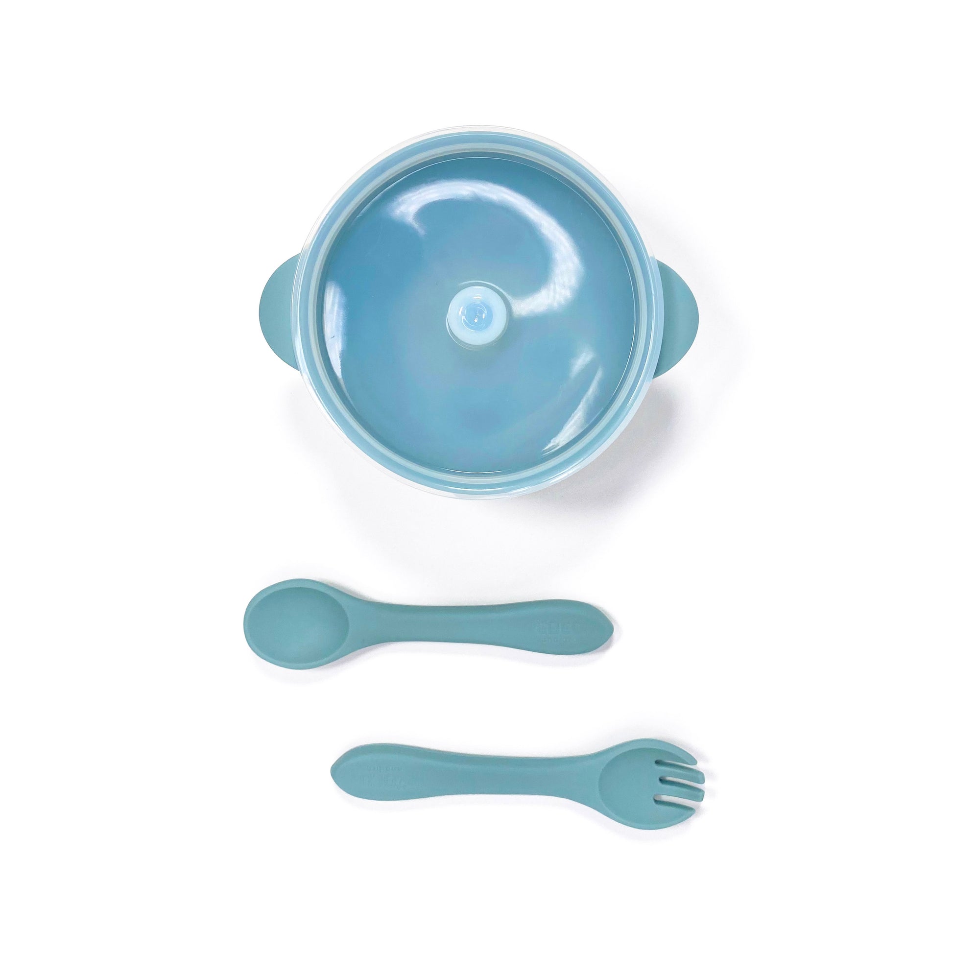 A sky blue silicone children’s feeding set, including silicone bowl with lid and matching silicone cutlery. Image shows the bowl and cutlery from above, with lid attached.