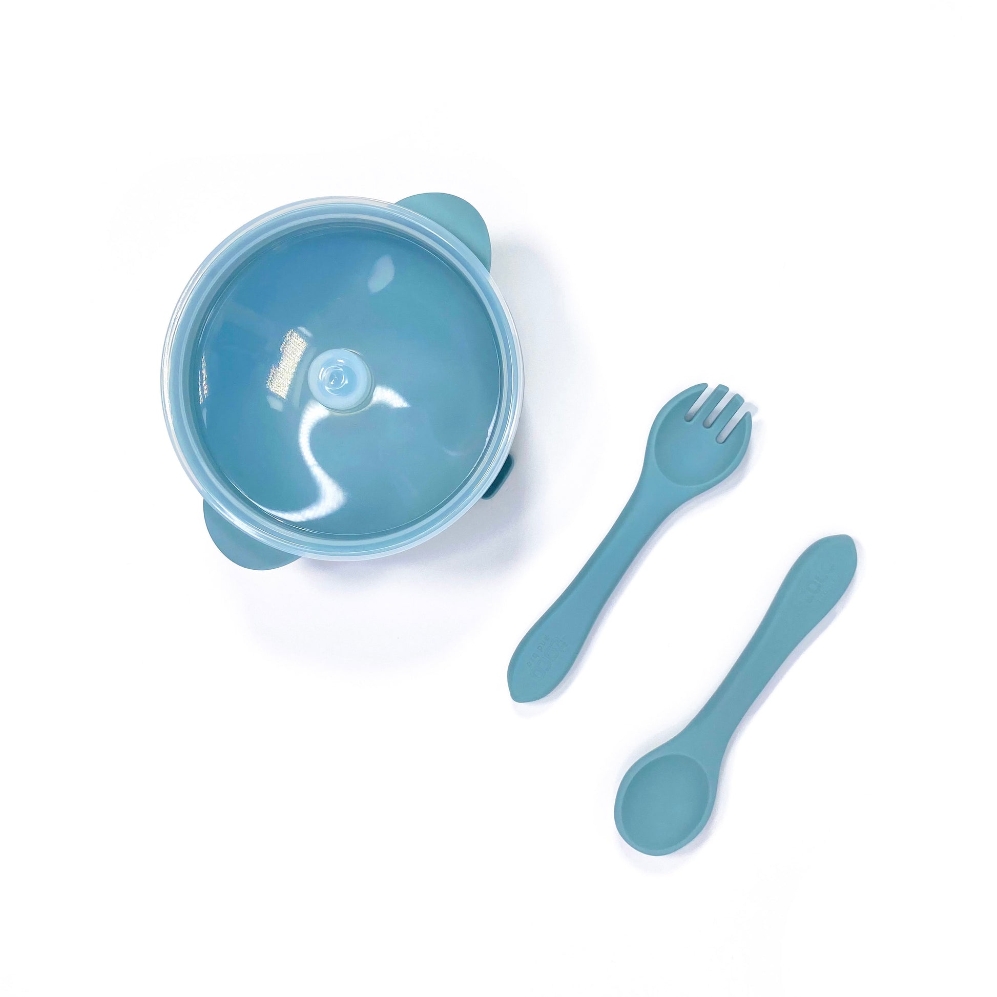 A sky blue silicone children’s feeding set, including silicone bowl with lid and matching silicone cutlery. Image shows the bowl and cutlery from above, with lid attached.
