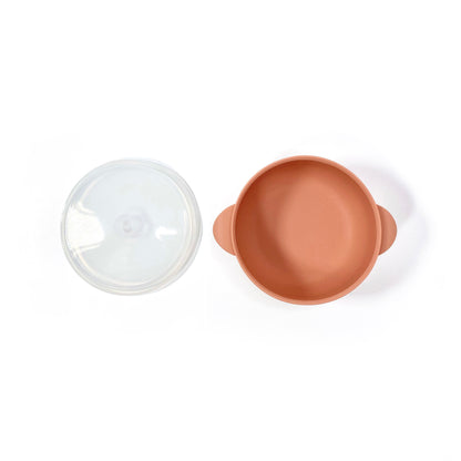 A sunset orange silicone children’s feeding bowl, with lid and suction cup. Image shows the bowl with lid separately.