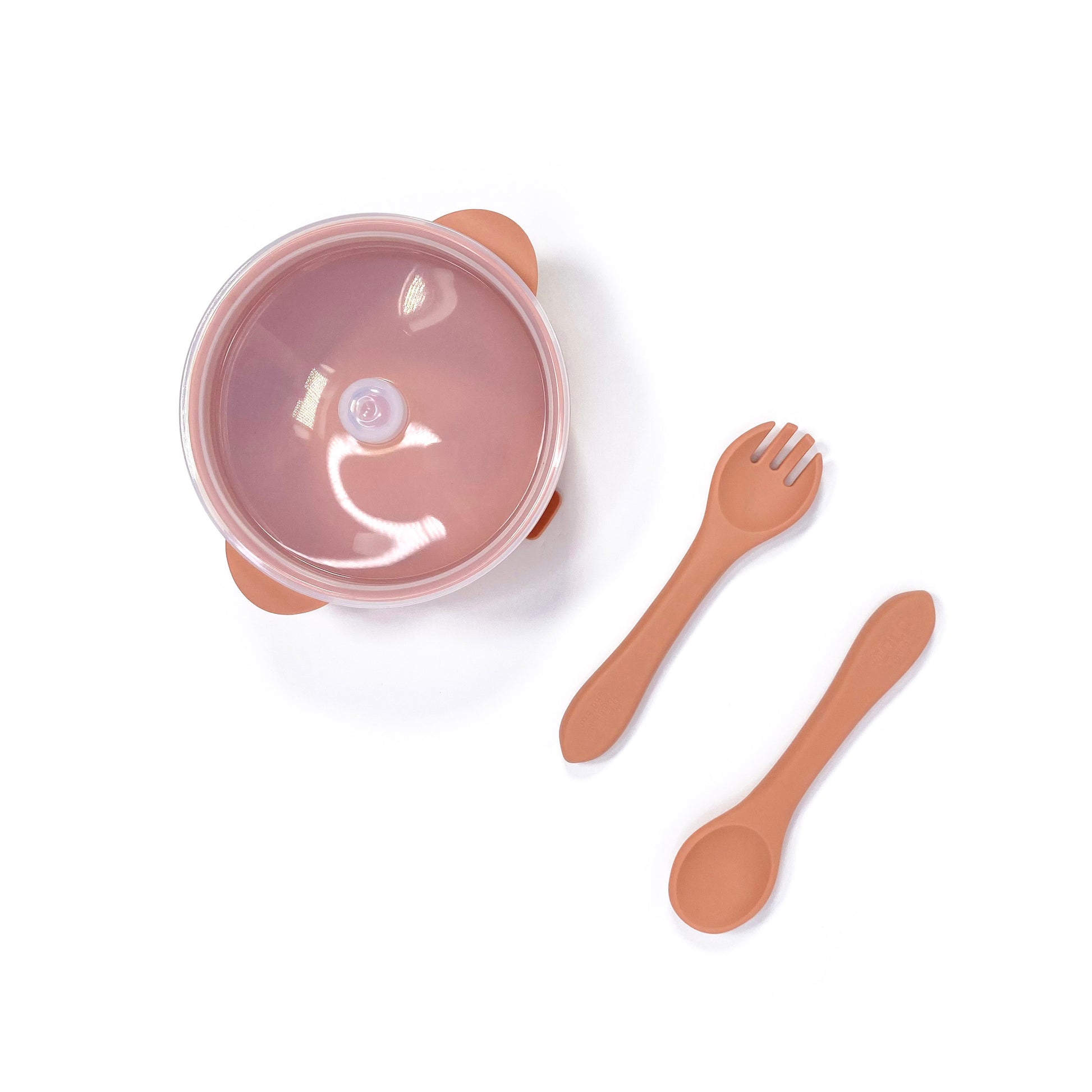 A sunset orange silicone children’s feeding set, including silicone bowl with lid and matching silicone cutlery. Image shows the bowl and cutlery from above, with lid attached.