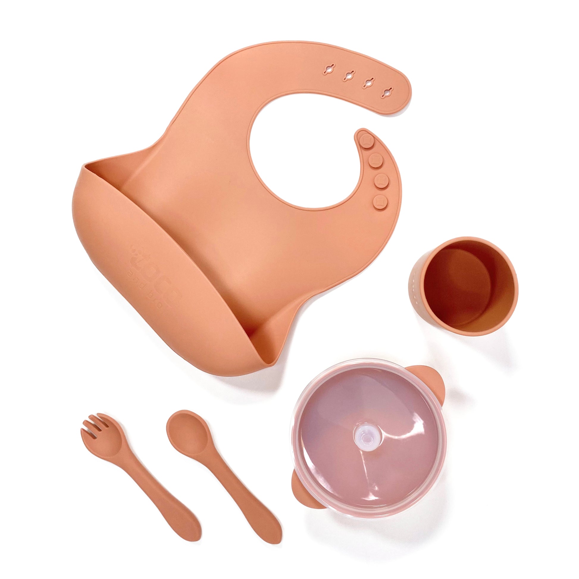 A sunset orange silicone children’s feeding set, including adjustable silicone bib with crumb catcher, silicone drinking cup, silicone bowl with lid and silicone cutlery.