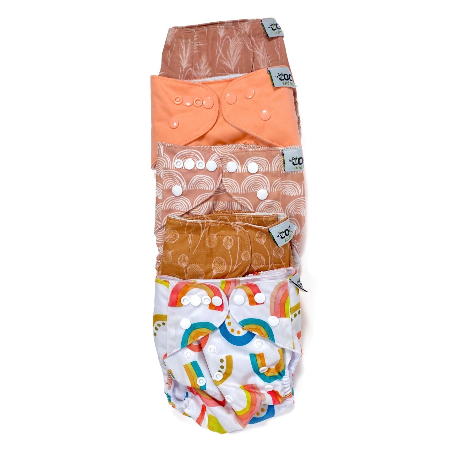 A set of five reusable nappies, made from 100% recycled polyester. The included nappies are: Bright Rainbow, Copper Bloom, Peach Rainbow, Cute Coral and Sunset Dune. View shows all five nappies front facing, in a vertical line.