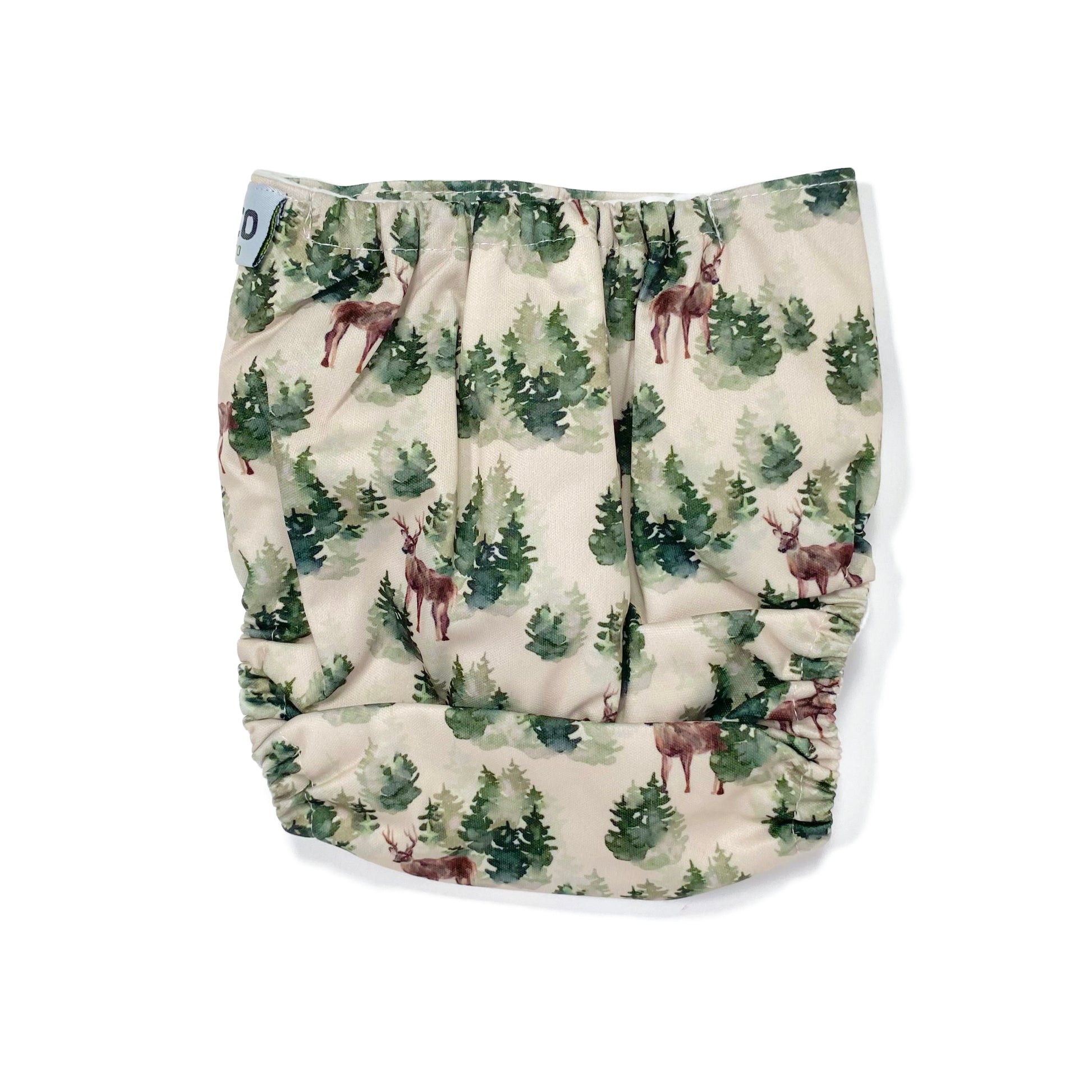 An adjustable reusable nappy for babies and toddlers, featuring a winter forest design with images of deer and pine trees on a cream background. View shows the back of the nappy.