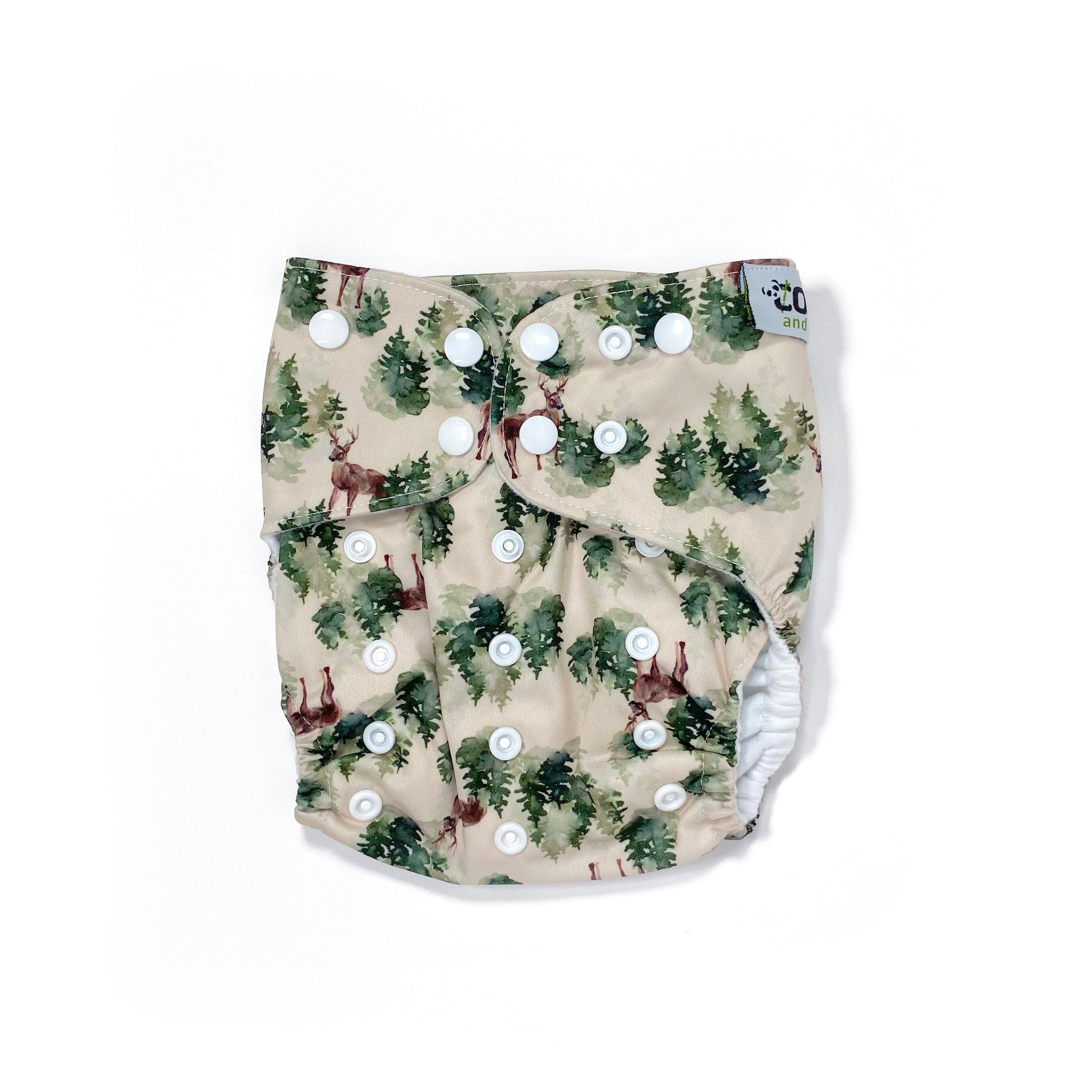 An adjustable reusable nappy for babies and toddlers, featuring a winter forest design with images of deer and pine trees on a cream background. View shows the front of the nappy, with fastenings closed.