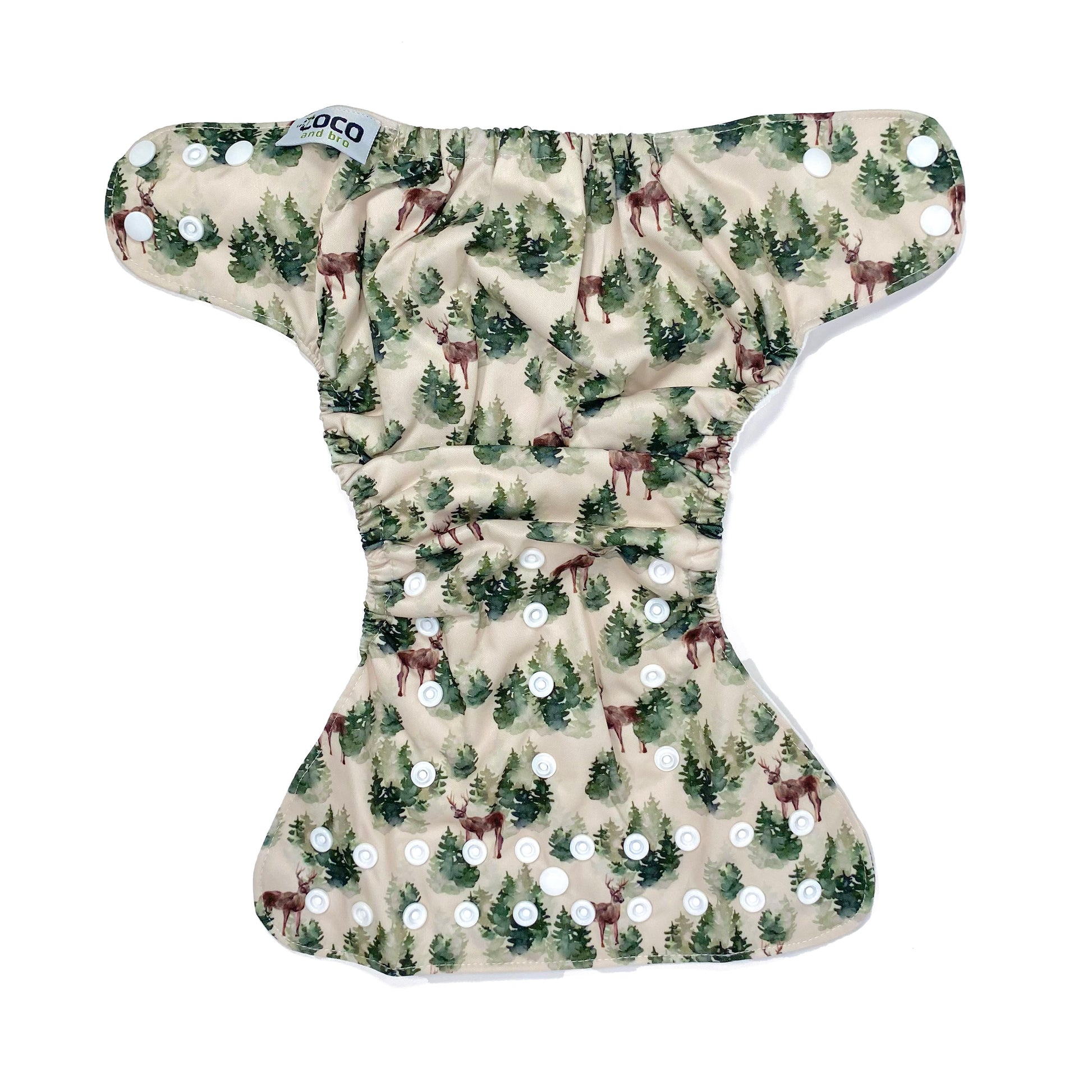 An adjustable reusable nappy for babies and toddlers, featuring a winter forest design with images of deer and pine trees on a cream background. View shows the full outside pattern of the nappy, with fastenings open.