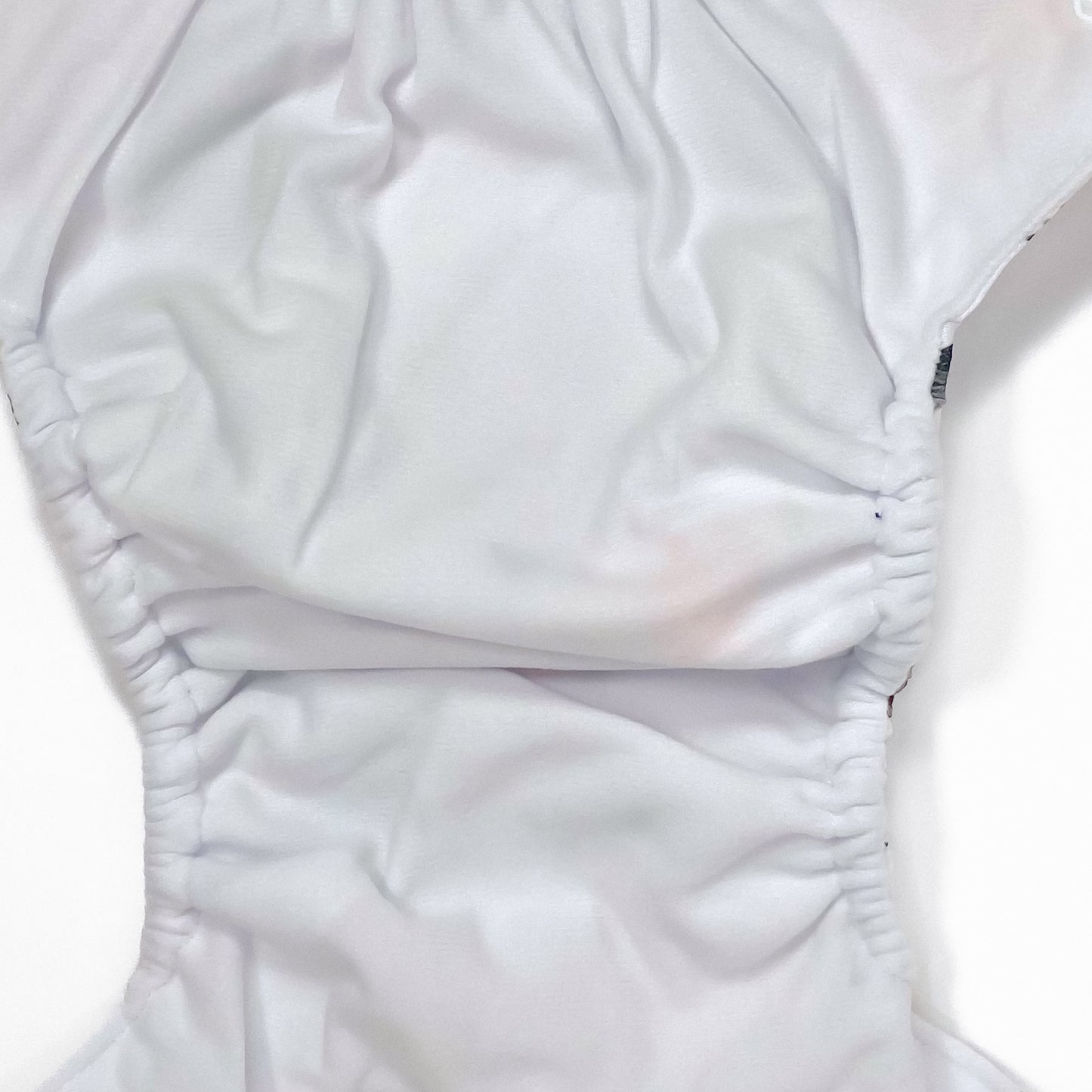 An adjustable reusable nappy for babies and toddlers, featuring a woodland animal design, with images of various woodland animals on a white background. Image shows a zoomed in view of the nappy fabric lining.