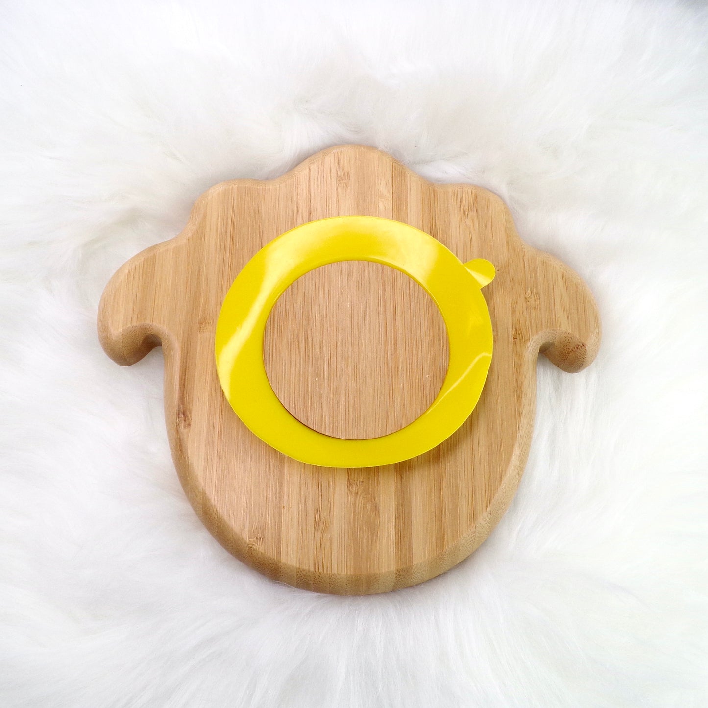 A children's bamboo section plate with a lamb design, yellow colour silicone suction ring and matching yellow bamboo and silicone cutlery. Back view.