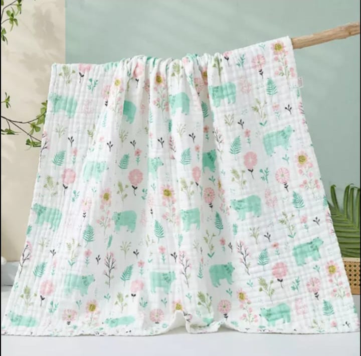 A large muslin baby blanket, made from bamboo and cotton fibres. This blanket is perfect for a baby nursery or out and about in a buggy. The blanket features a cute green bear pattern.