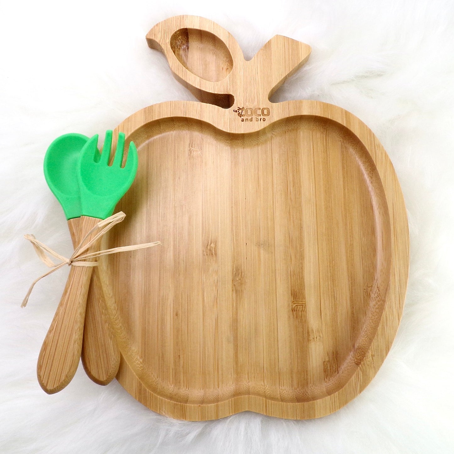 A bamboo children’s plate, with multiple food sections, in an apple design. The bamboo plate features a green silicone suction ring at the back, and includes bamboo fork and spoon utensils in matching colours. Front view.
