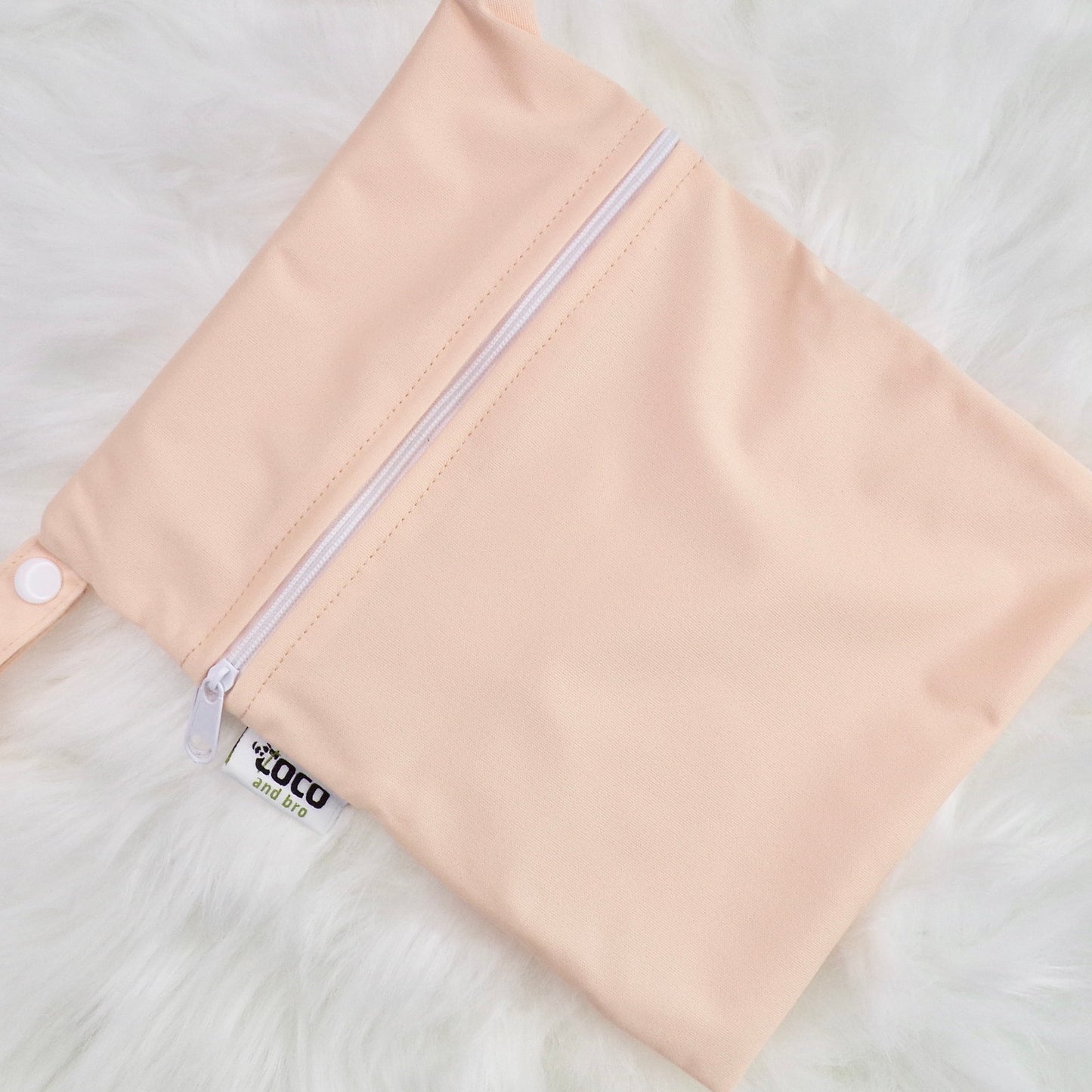 Each backpack purchase includes a free waterproof bag. This image shows the waterproof bag in peachy pink, with a zip closure.