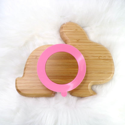 A bamboo children’s plate, with multiple food sections, in a rabbit design. The bamboo plate features a pink silicone suction ring at the back, and includes bamboo fork and spoon utensils in matching colours. Back view.