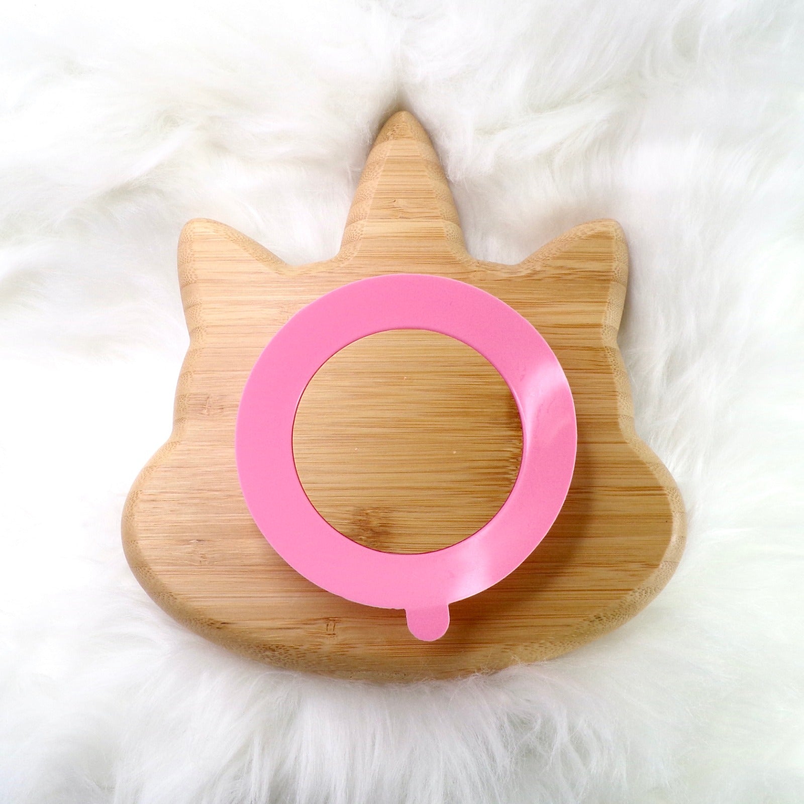 A bamboo children’s plate, with multiple food sections, in a unicorn design. The bamboo plate features a pink silicone suction ring at the back, and includes bamboo fork and spoon utensils in matching colours. Back view.