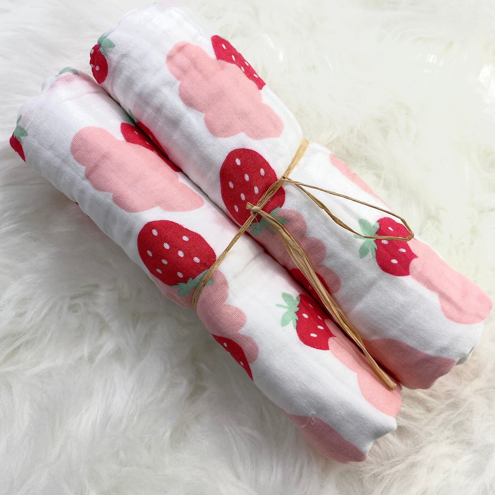 A large muslin baby blanket, made from bamboo and cotton fibres. This blanket is perfect for a baby nursery or out and about in a buggy. The blanket features a cute pink clouds and strawberries pattern.