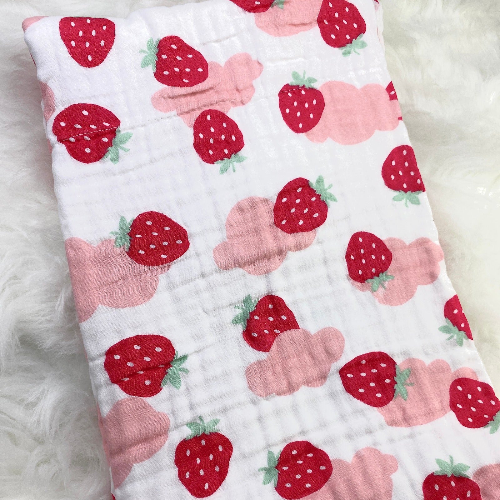 A large muslin baby blanket, made from bamboo and cotton fibres. This blanket is perfect for a baby nursery or out and about in a buggy. The blanket features a cute pink cloud and strawberries pattern.