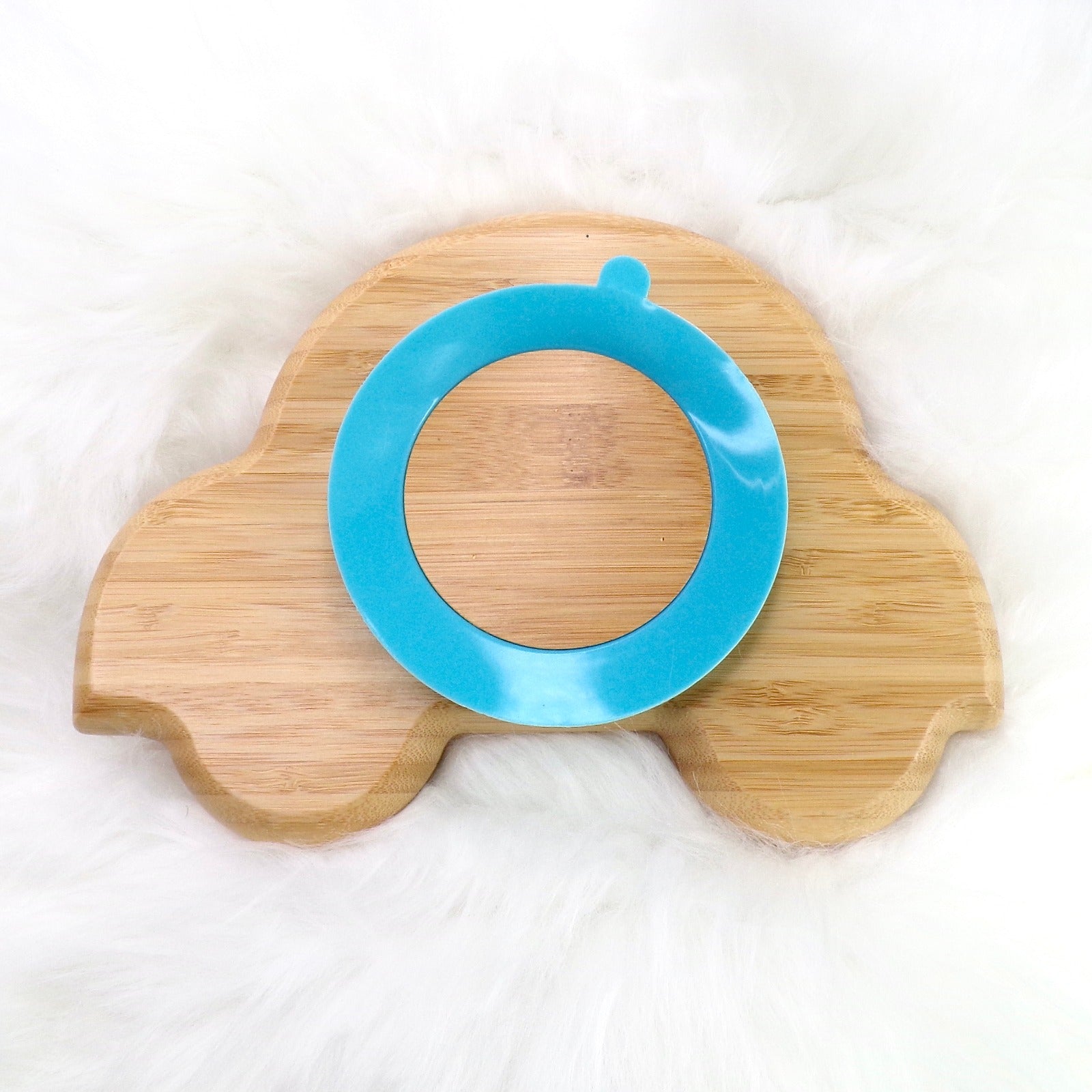 A bamboo children’s plate, with multiple food sections, in a car design. The bamboo plate features a blue silicone suction ring at the back, and includes bamboo fork and spoon utensils in matching colours. Back view.