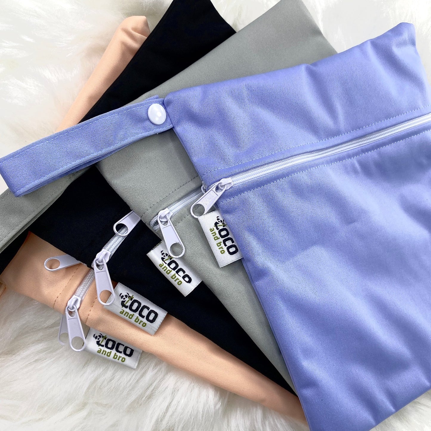 A selection of waterproof bags. Each backpack purchase includes a free waterproof bag. The bags are made from bamboo, and are available in black, grey, purple and peachy pink.